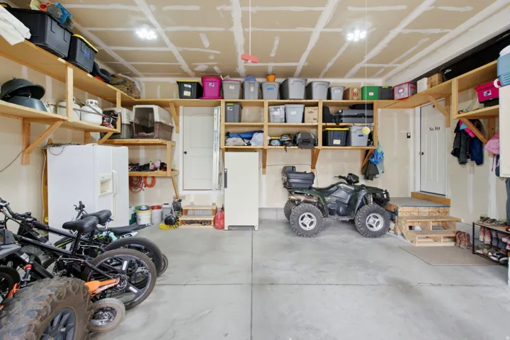 Concrete flooring with two overhead light fixtures, built-in wooden shelving, and two interior doors