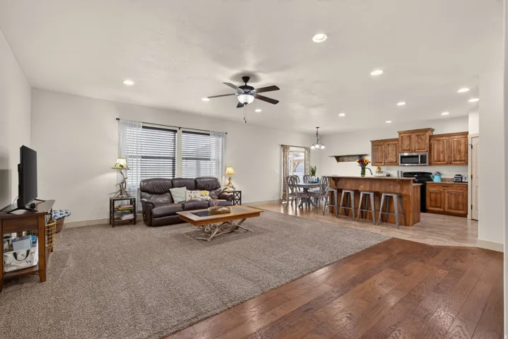 Open-concept living area with wood-finish flooring, recessed lighting, and a ceiling fan
