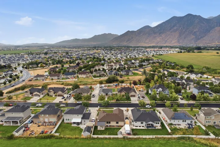 Residential neighborhood featuring diverse architectural styles, mature landscaping, paved streets, and a mountain backdrop