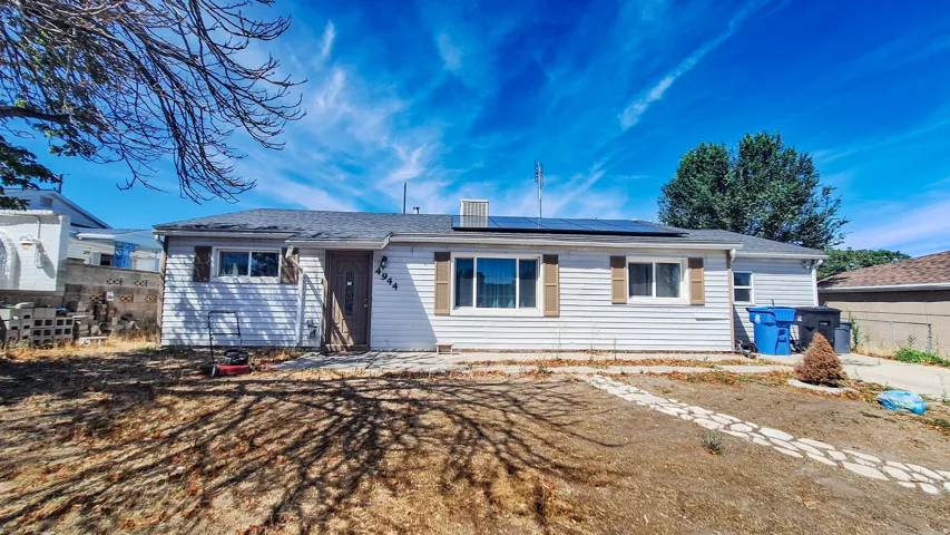 Charming single-story residence featuring white vinyl siding, multiple windows providing natural light, and a spacious front-facing yard with mature landscaping