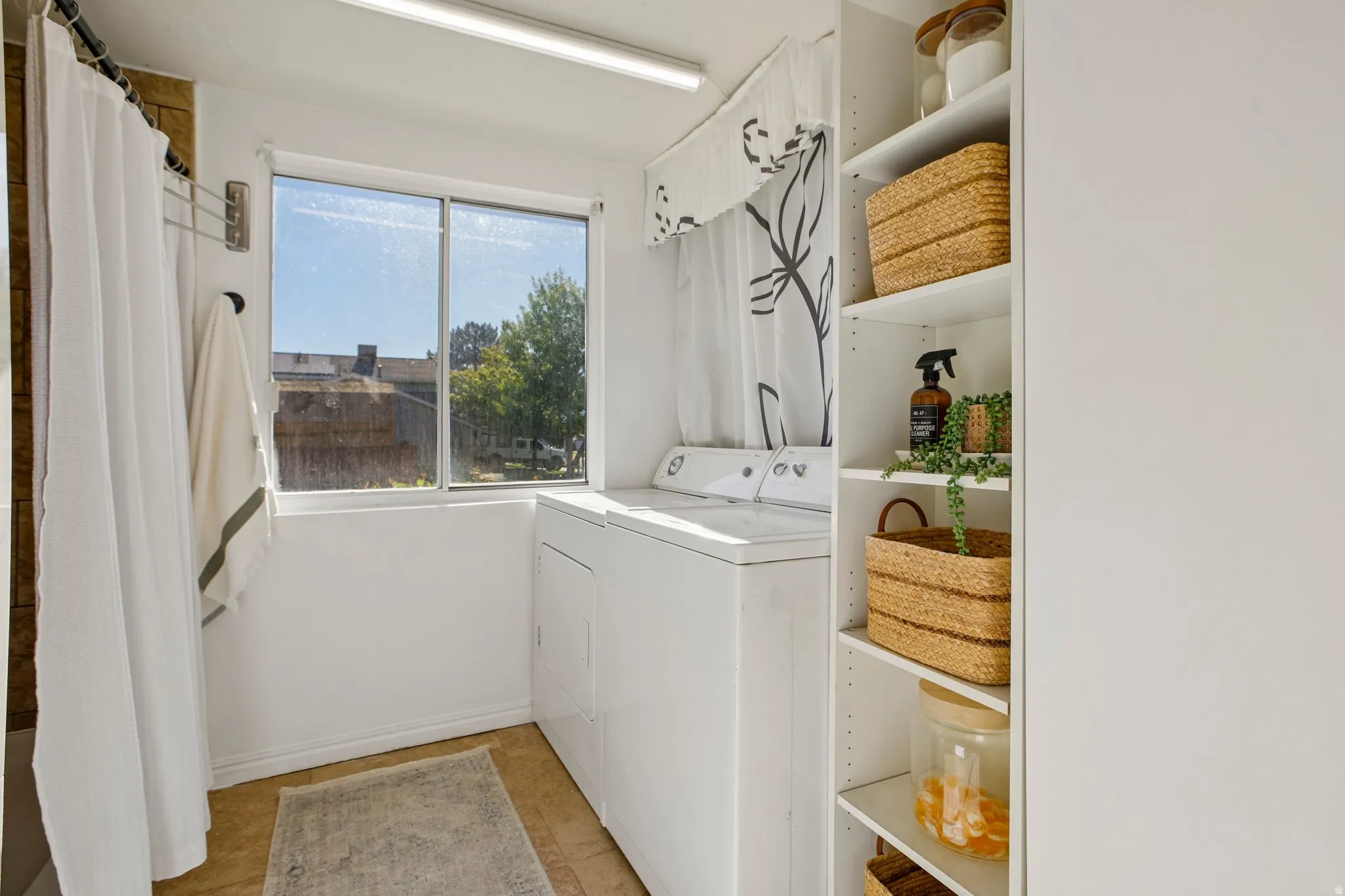 Dedicated laundry area featuring a window, built-in shelving, and a combination washer and dryer