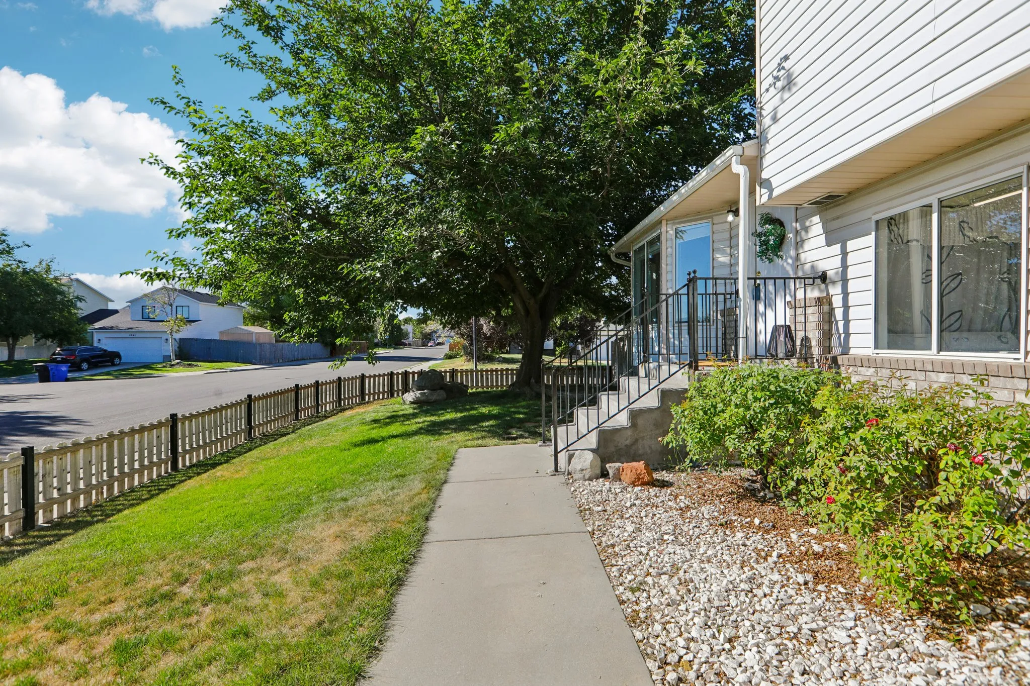 Siding exterior with a covered entry, concrete walkway, and decorative fencing