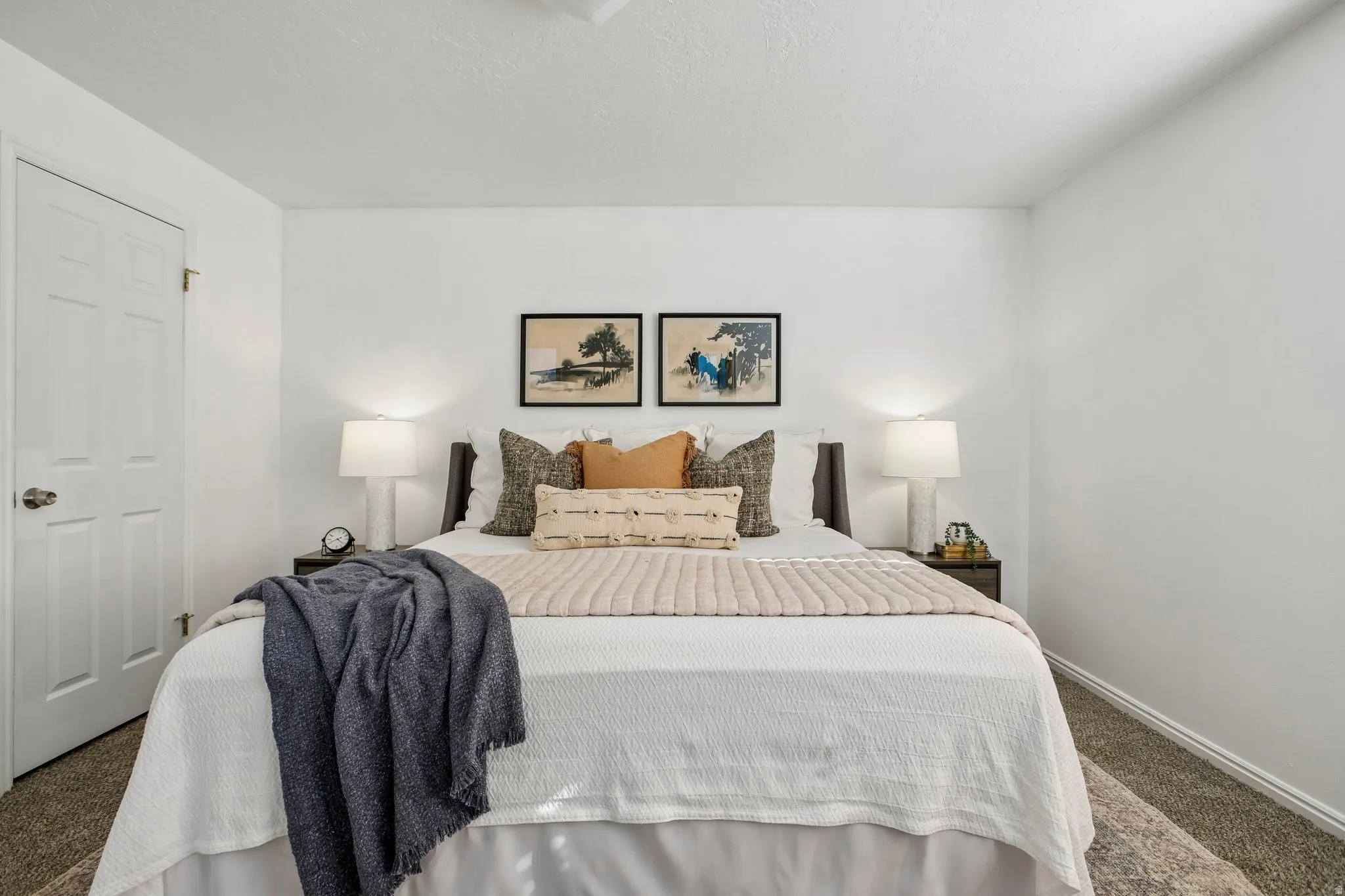 Bedroom featuring white painted walls, a textured carpet, and a paneled interior door