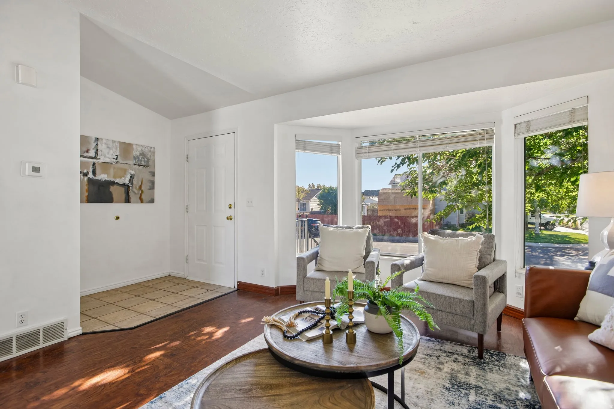 Bay window with multiple panes, wood-finish flooring, white trim, and a tile entry