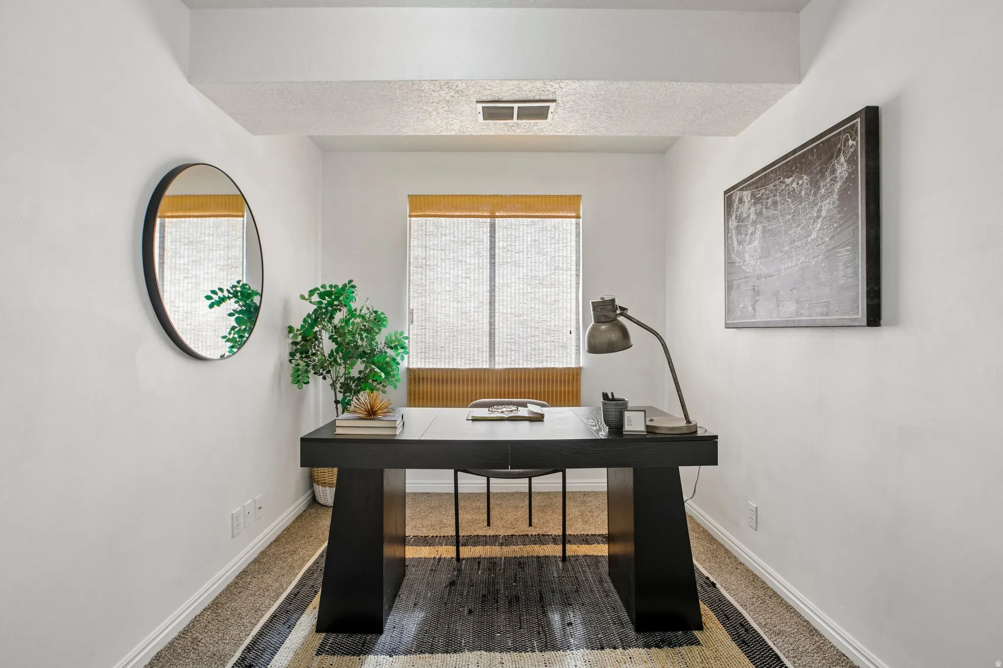 Window with natural fiber shades, white painted walls, and carpet flooring