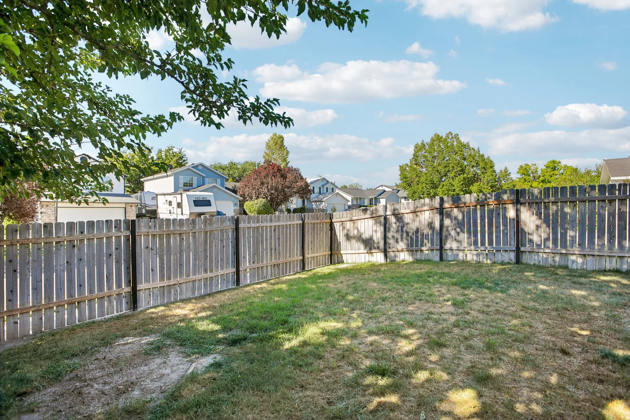 Enclosed backyard featuring wood fencing and established trees