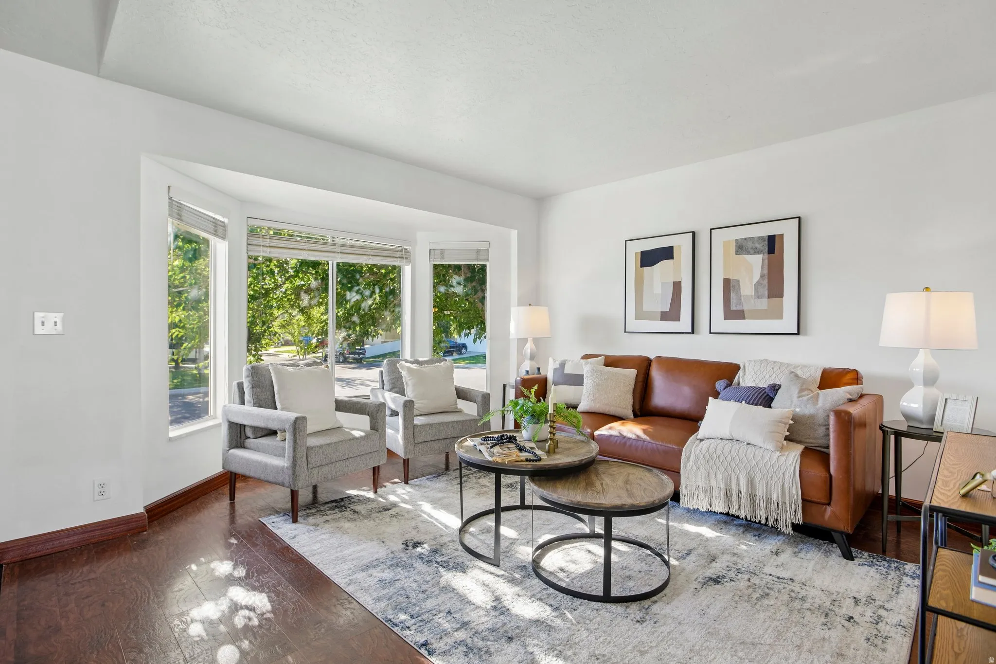 Spacious living area featuring a bay window, wood-finish flooring, and crisp white walls