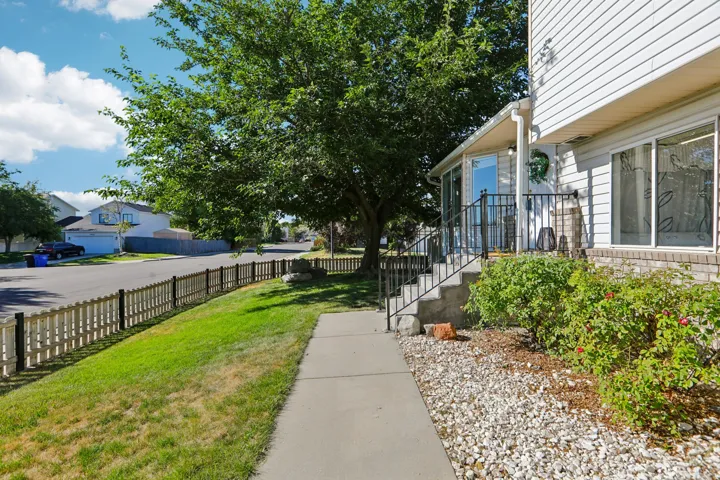 Siding exterior with a covered entry, concrete walkway, and decorative fencing
