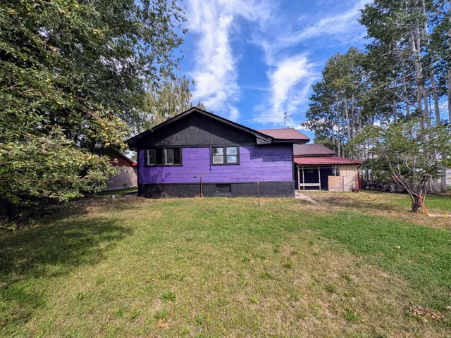 Property exterior featuring a purple siding, black trim, and a red metal roof