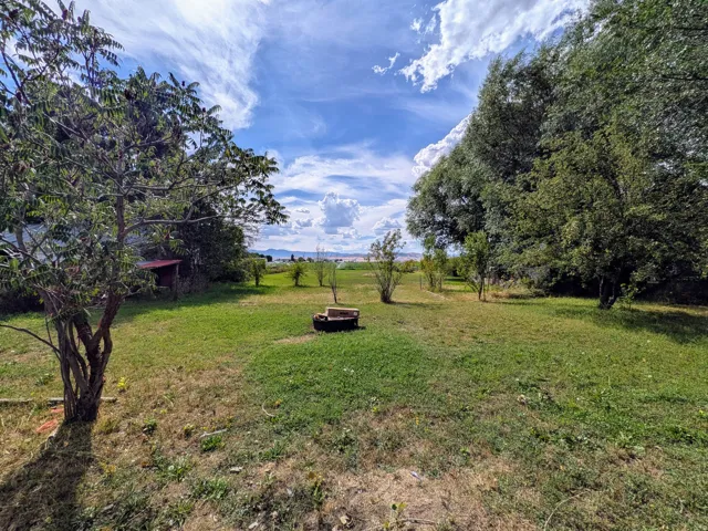 Expansive grassy lot with mature trees and distant mountain scenery