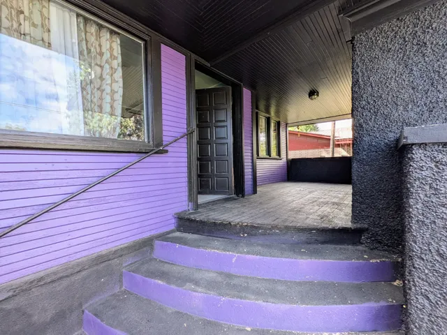 Covered porch with wood panel ceiling, exterior siding, multi-panel entry door, and concrete steps