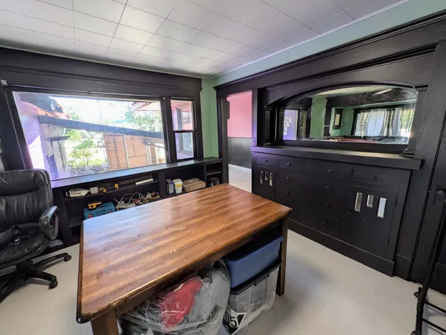 Expansive window with integrated storage shelving, dark wood trim throughout, and a built-in credenza with an arched mirror feature