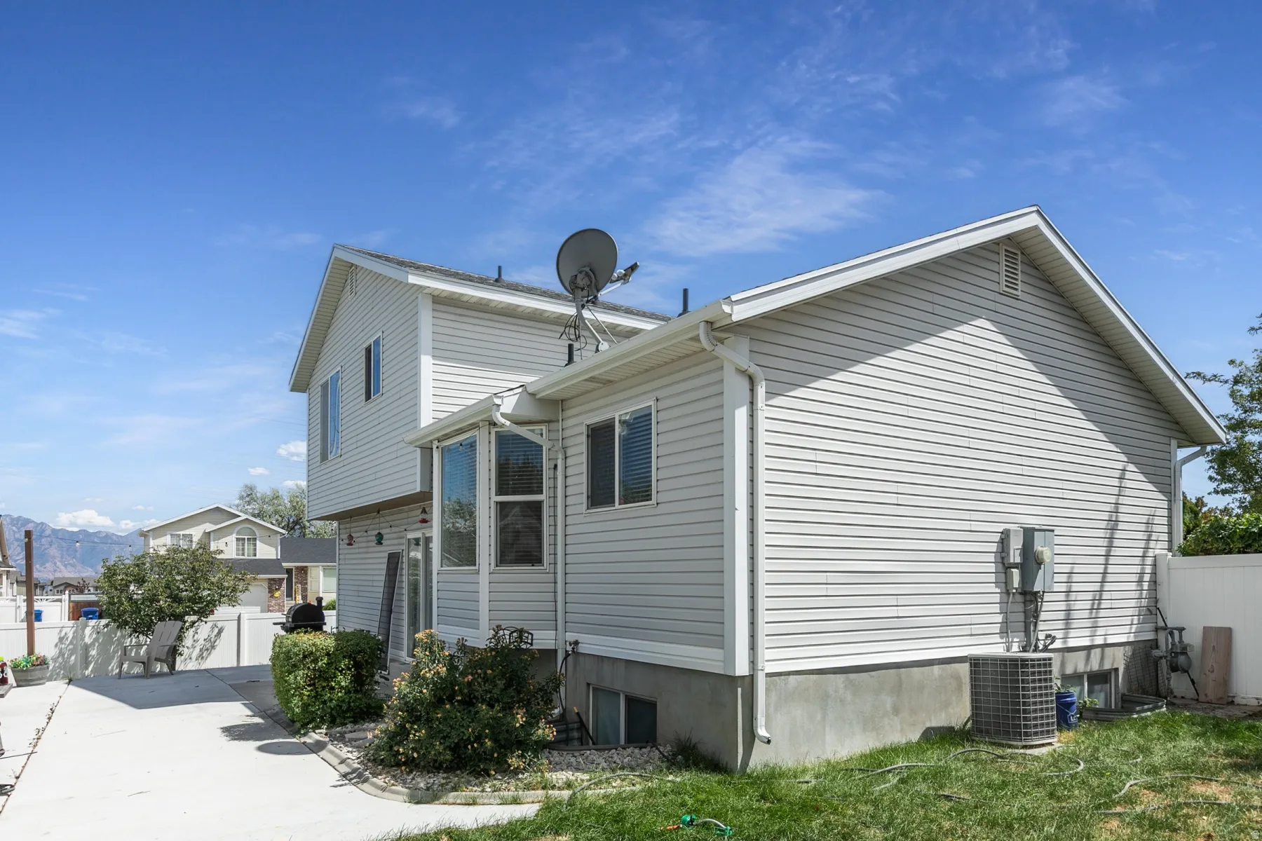 Two-story exterior with light-colored siding, a pitched roof, multiple windows, and a paved side yard