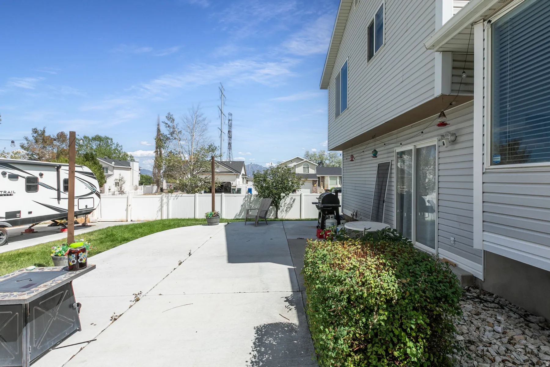 Rear exterior with light gray siding, sliding glass door, and a concrete patio