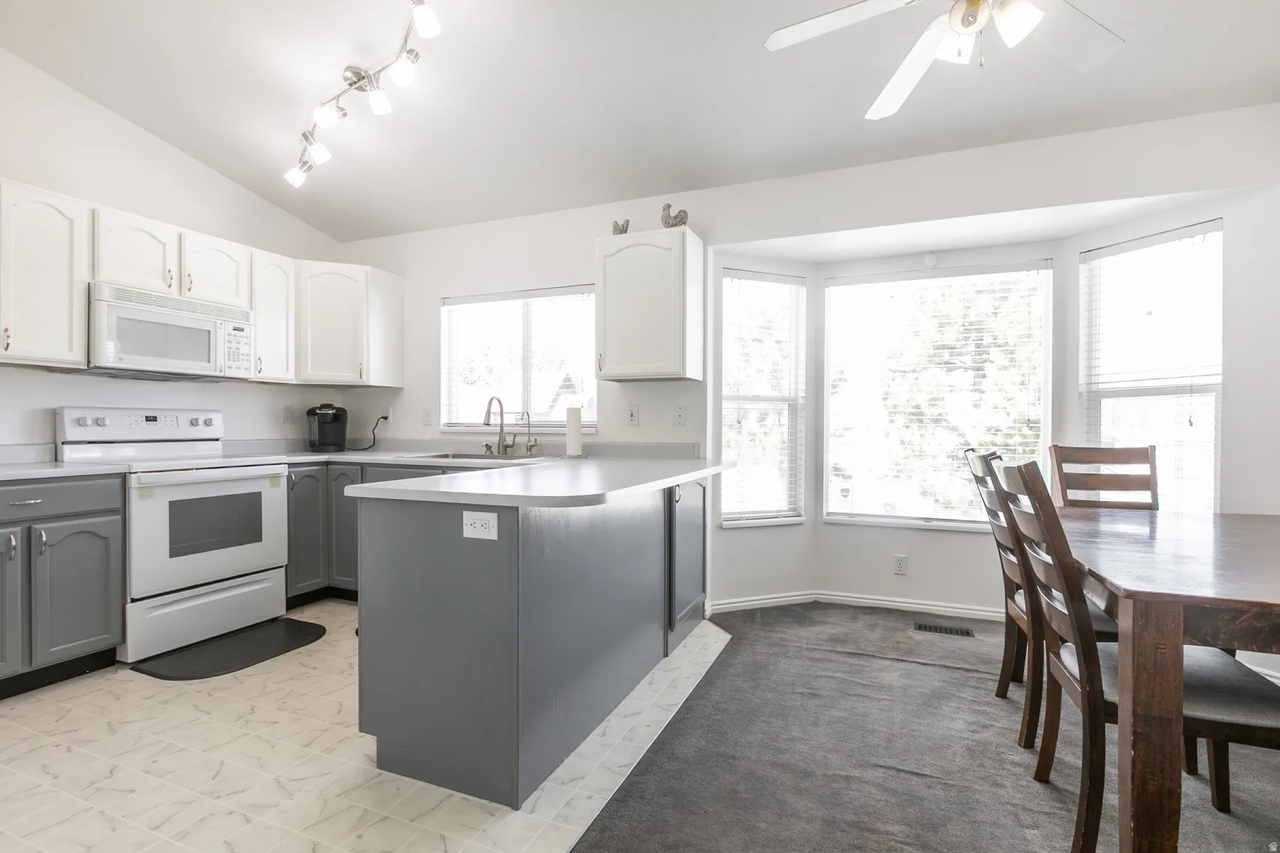 Kitchen featuring two-tone cabinetry, white appliances, and a central island