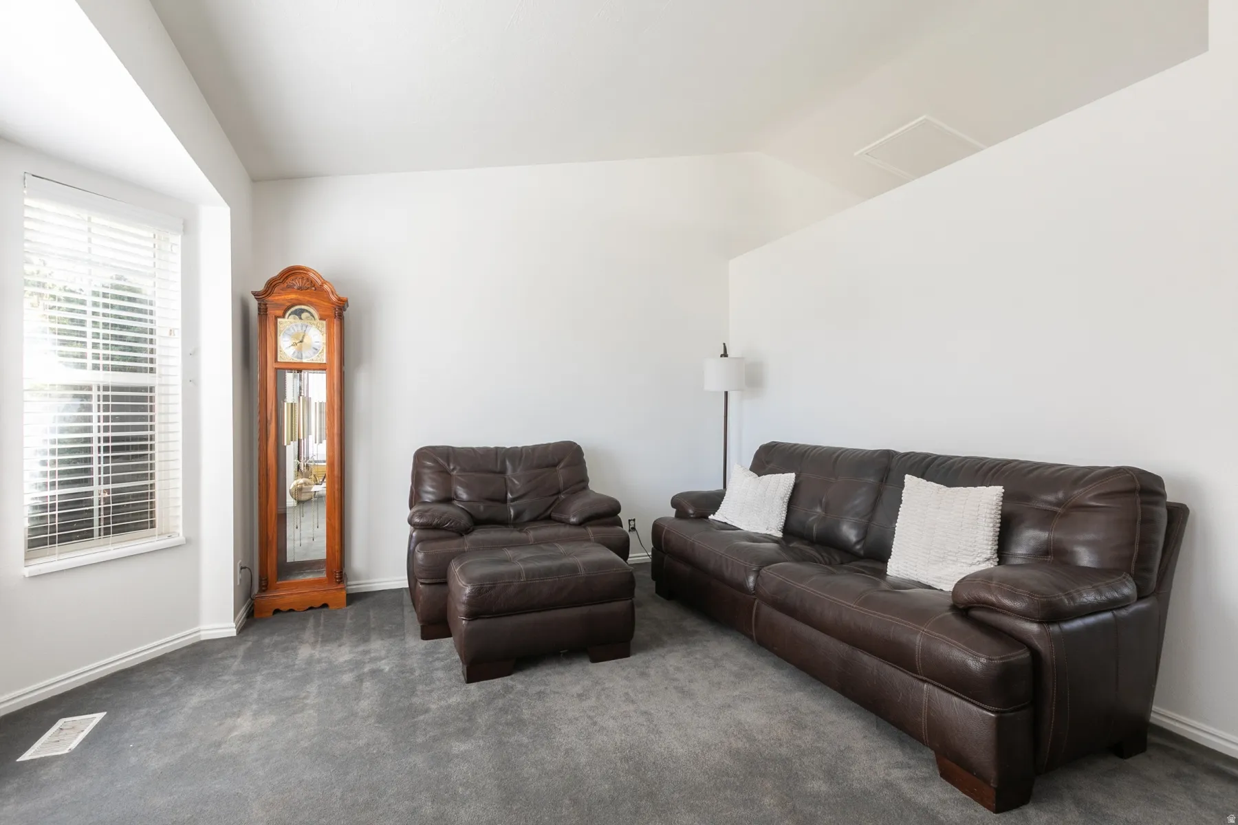 Wall-to-wall carpeting with a vaulted ceiling and window with blinds