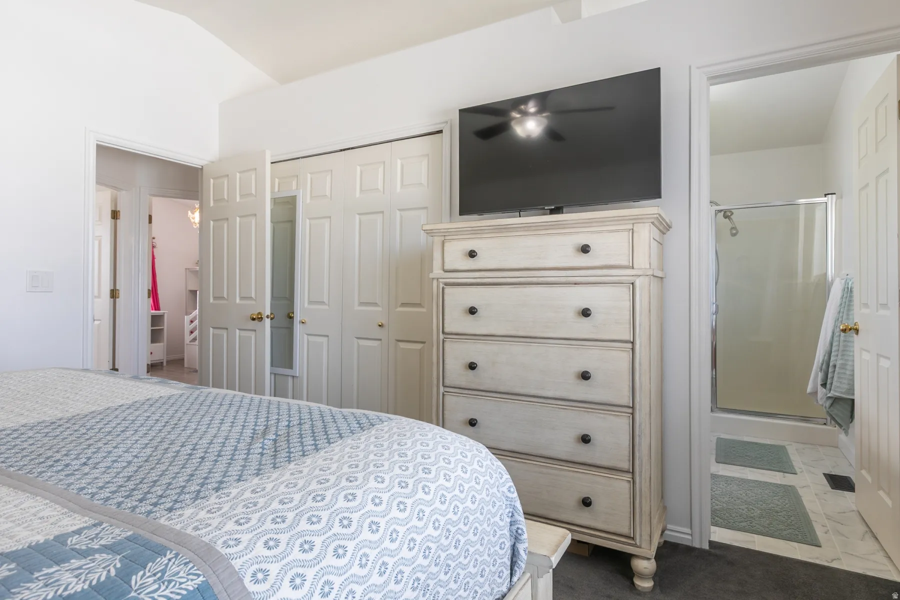 Vaulted ceiling, paneled closet doors, and a bathroom with a glass-enclosed shower