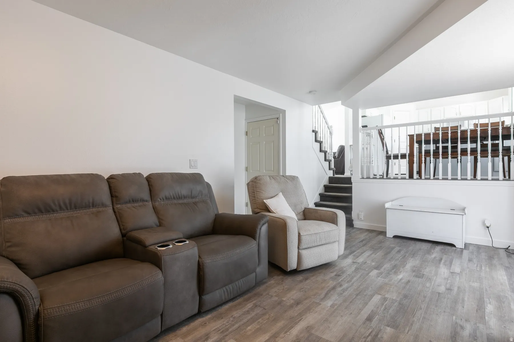 Wood-finish flooring, white wall finishes, and a staircase with white balusters