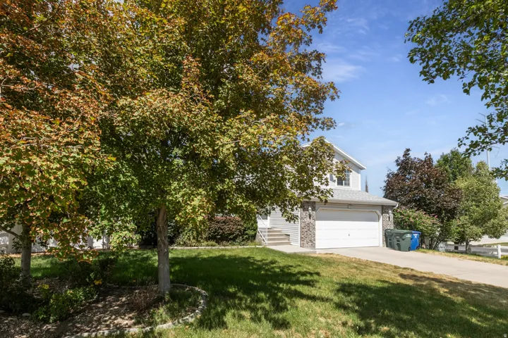 Two-story residence featuring light gray siding with stone-clad accents and a two-car garage