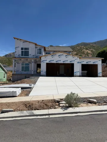 New construction showcasing a contemporary architectural style with multiple large windows, a newly poured concrete driveway, and a partially finished attached garage