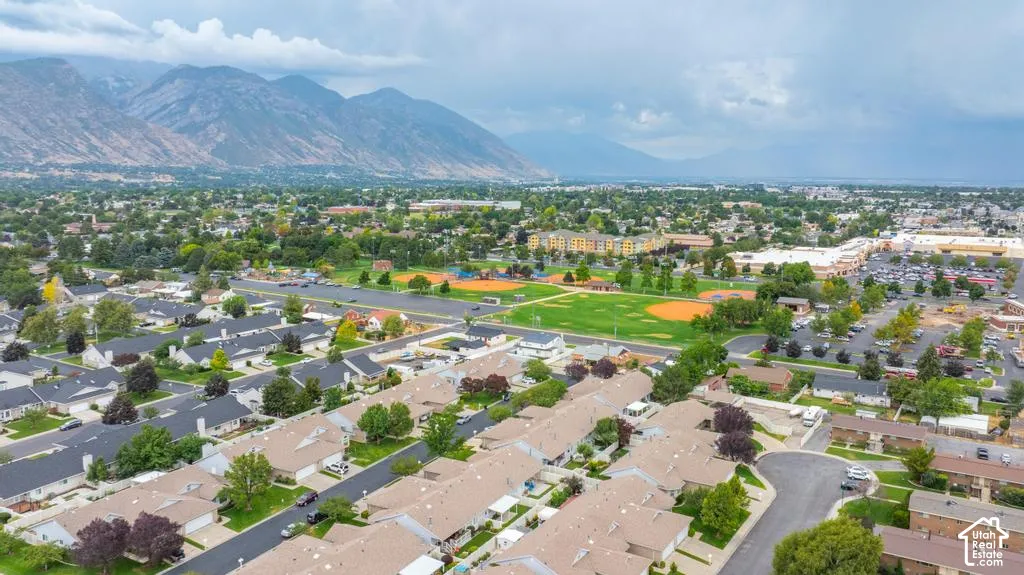 Expansive neighborhood with mountain backdrop, residential properties, green spaces, and commercial structures