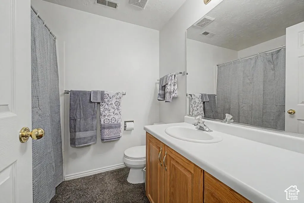 Single vanity with a white countertop and integrated sink, chrome faucet, and wood-finish cabinetry