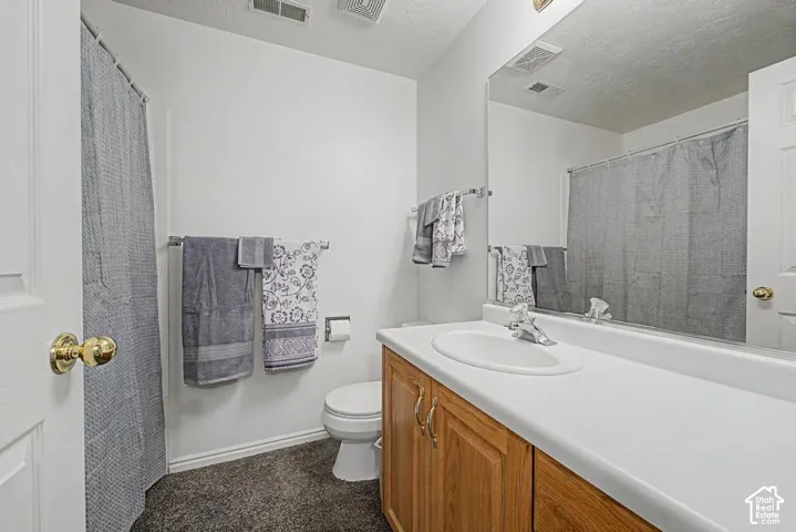 Single vanity with a white countertop and integrated sink, chrome faucet, and wood-finish cabinetry