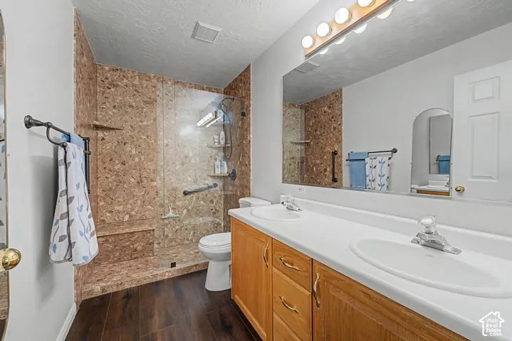 Wood-finish flooring with a double vanity featuring integrated sinks, ample counter space, and wood cabinetry