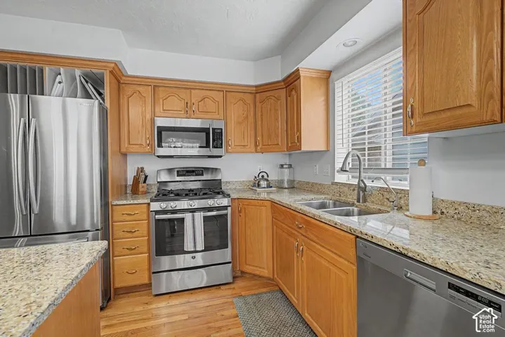 Stainless steel appliances, light wood cabinetry, dual basin stainless steel sink, light granite countertops, and hard wood floors.