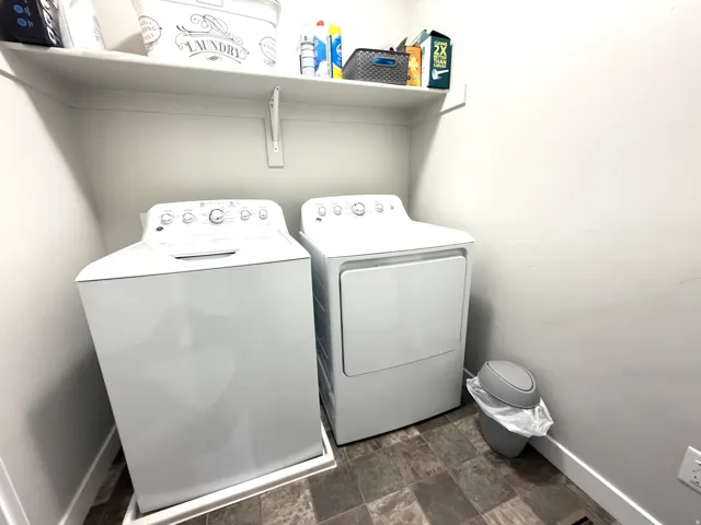 Utility area featuring a built-in wall shelf, a top-load washing machine, and a front-load dryer