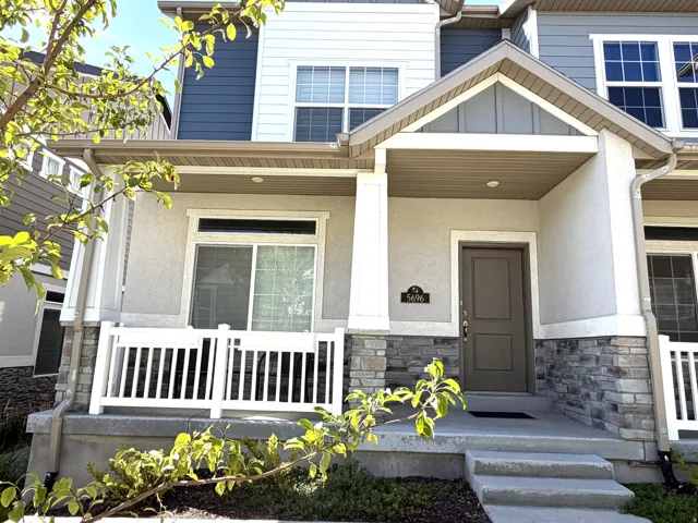 Multi-level facade with stone veneer accents, covered entry, and white column supports