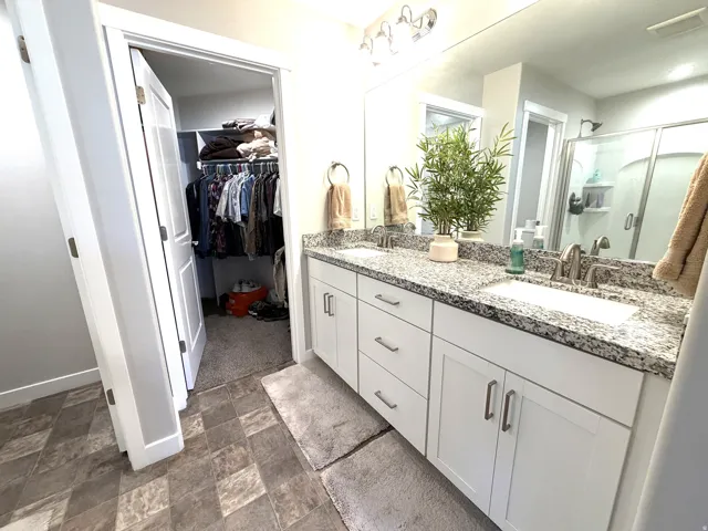 Dual vanity with granite-style countertop, white cabinetry, and brushed nickel hardware