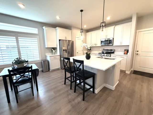 White cabinetry with brushed nickel hardware, stainless steel appliances, and a kitchen island with seating