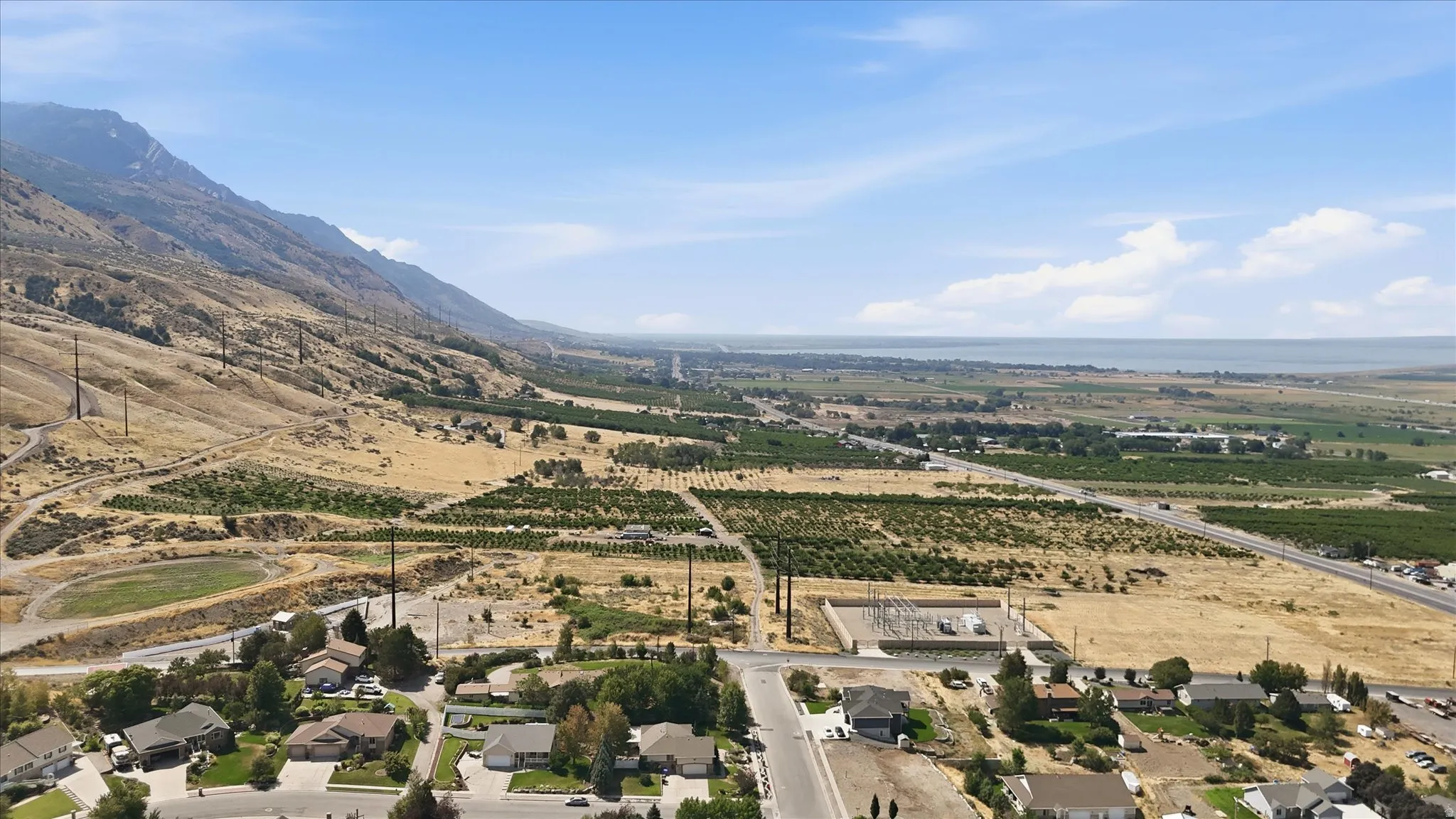 Expansive regional landscape featuring distant mountains, agricultural fields, and a large body of water