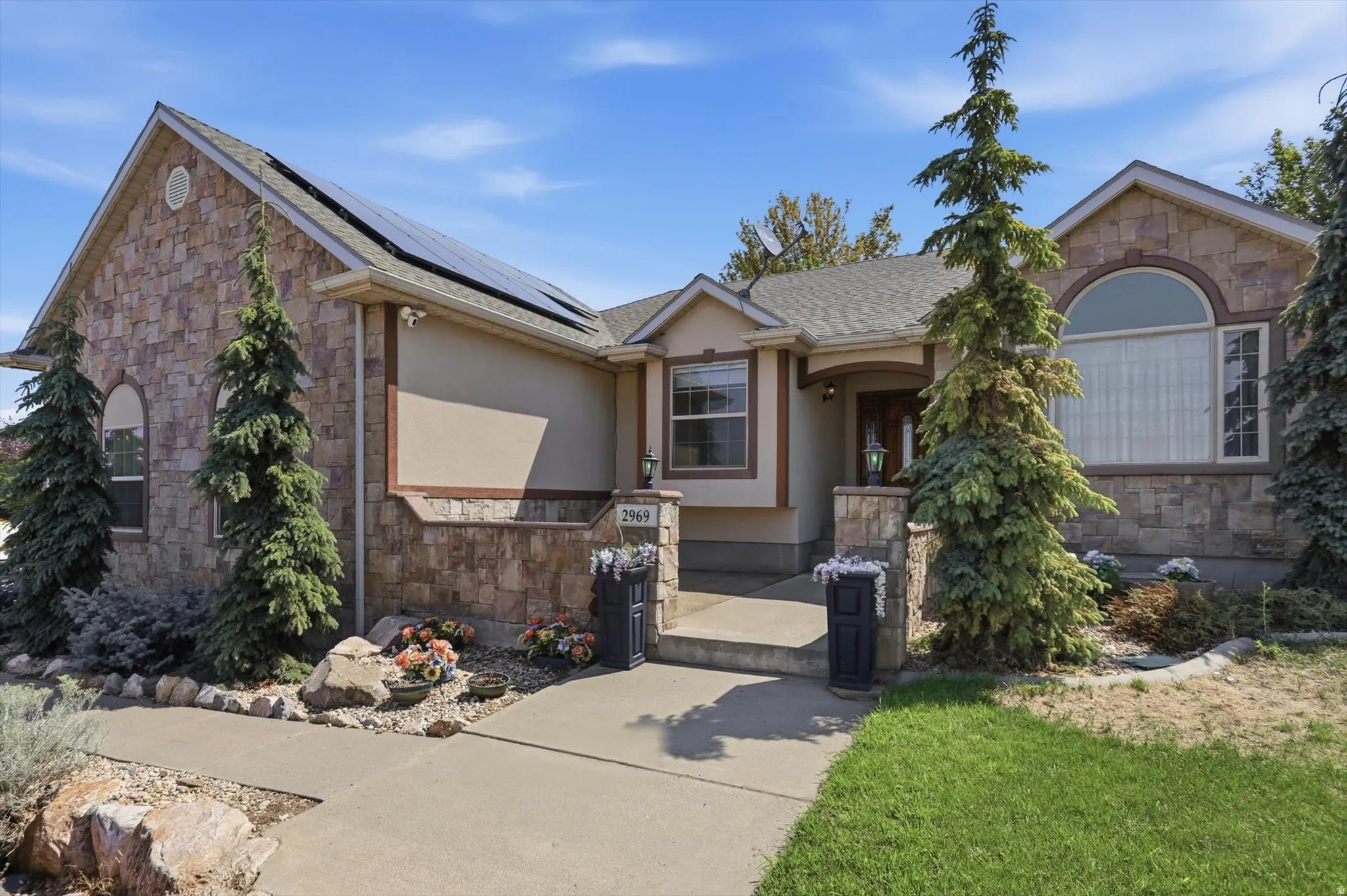 Stone veneer exterior with stucco accents, arched windows, and solar panel installation