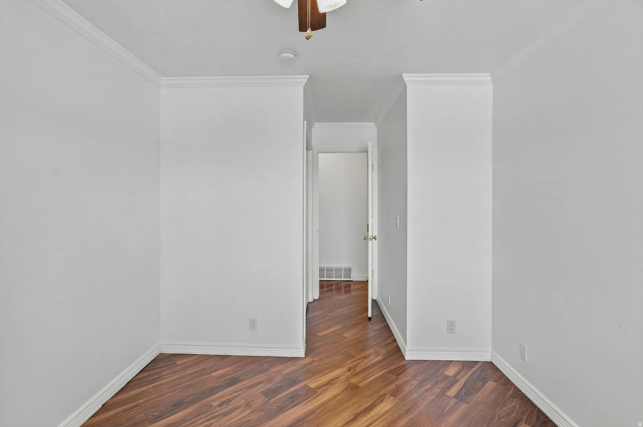 Wood-finish flooring with crown molding and white walls
