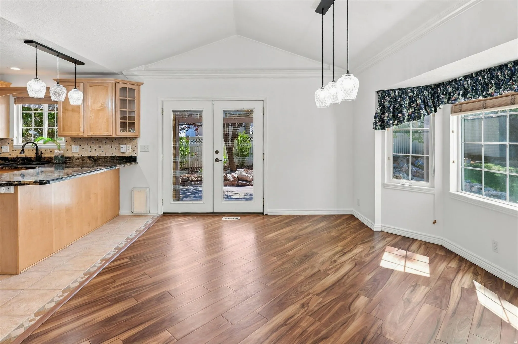 Wood-finish flooring, vaulted ceiling, and dual pendant lighting fixtures