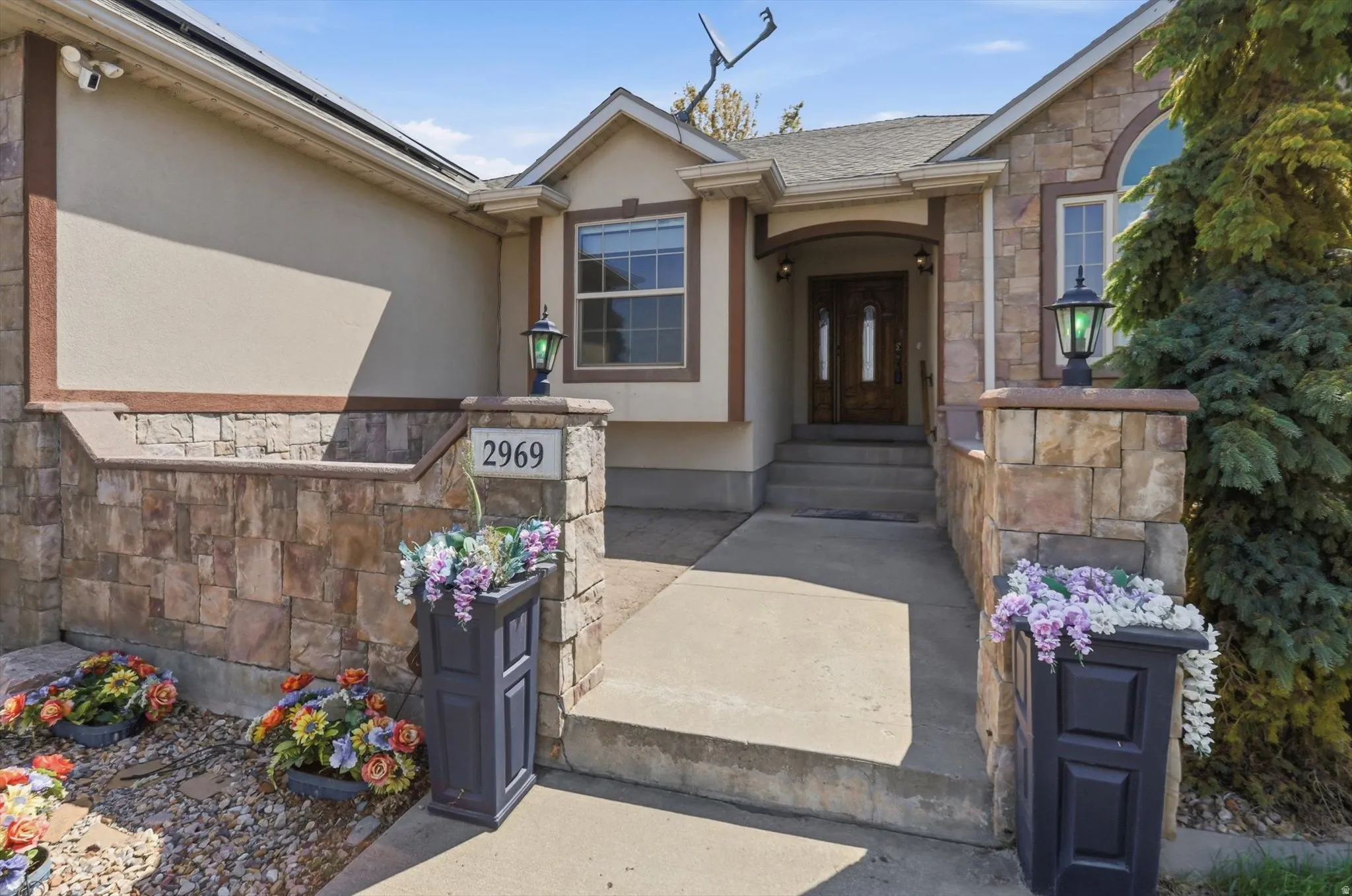 Stucco exterior with stone accents, arched entryway, double front doors, and an arched window