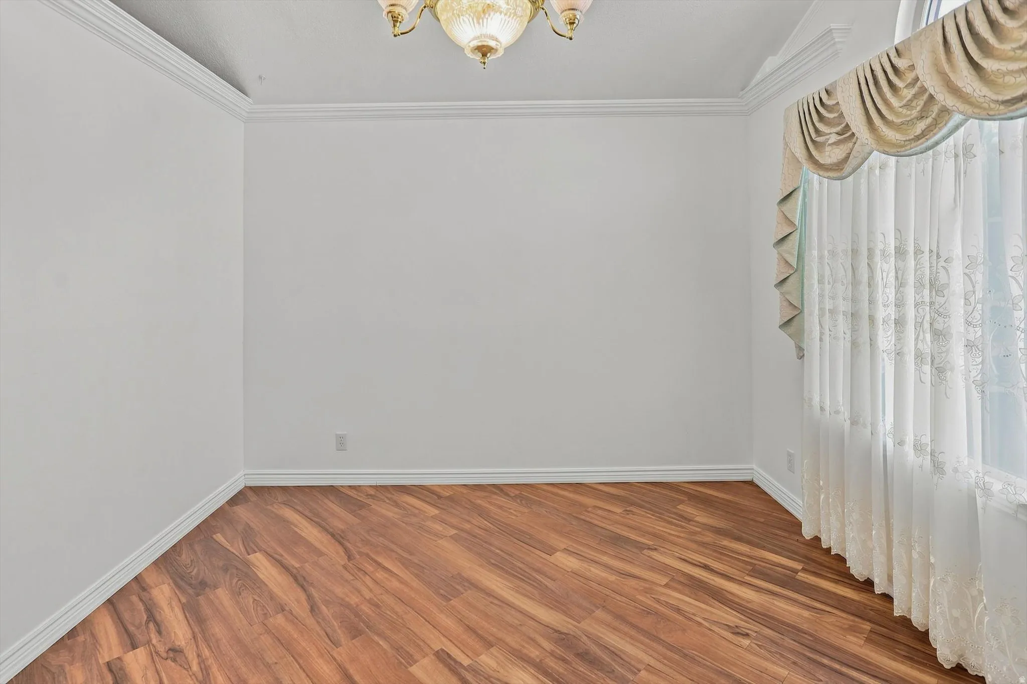 Wood-finish flooring, crown molding, and a chandelier