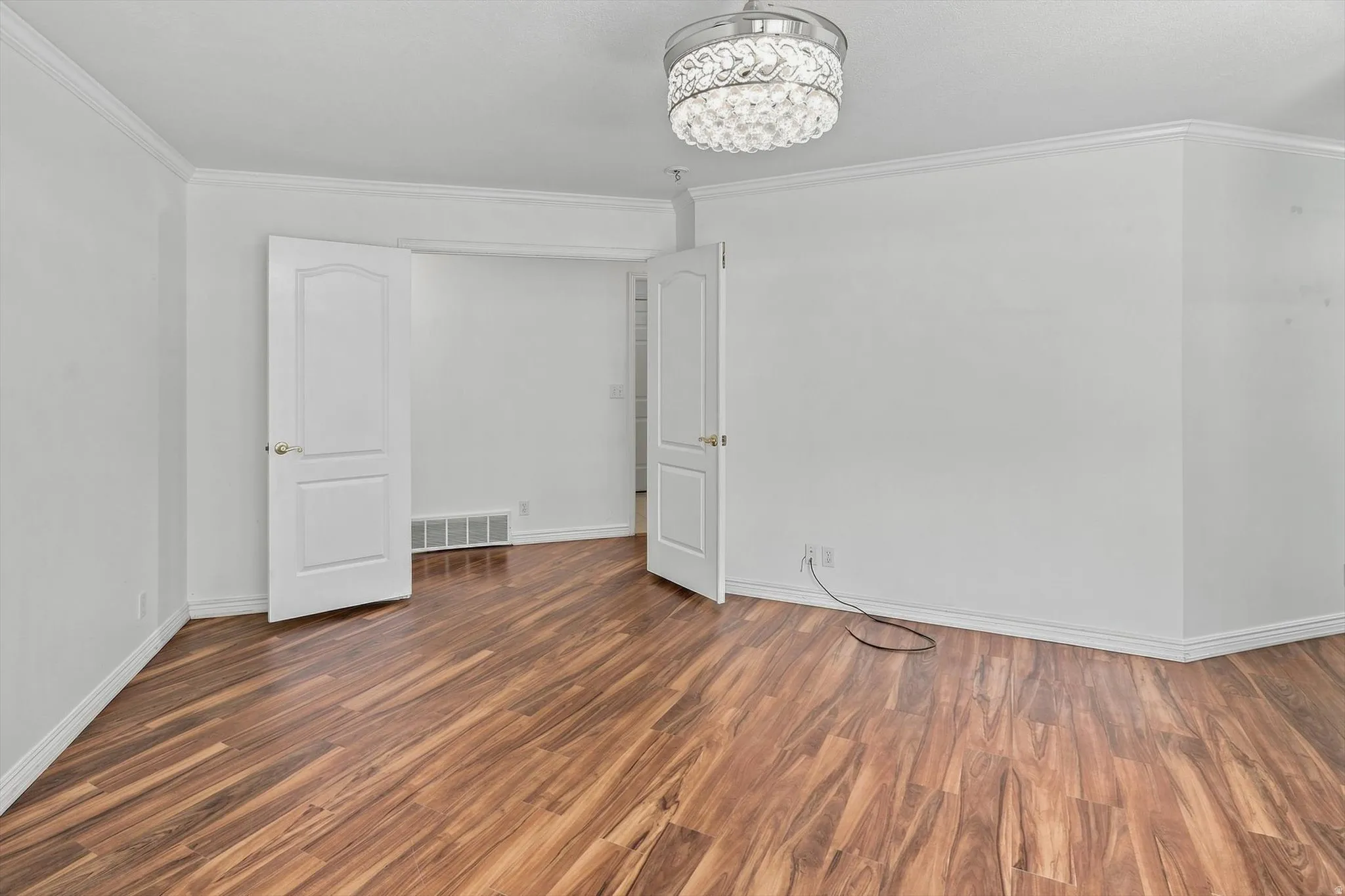 Wood-finish flooring, white trim, and crown molding