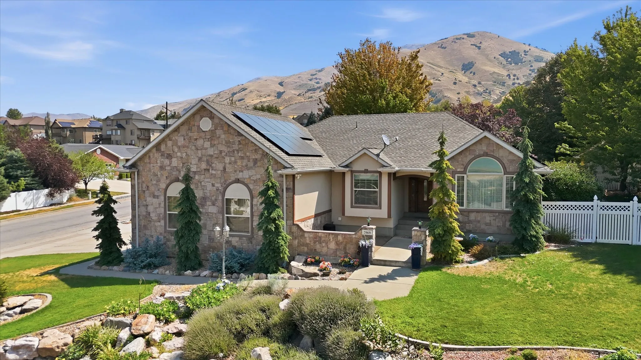 Stone veneer exterior with a gabled roof and solar panels