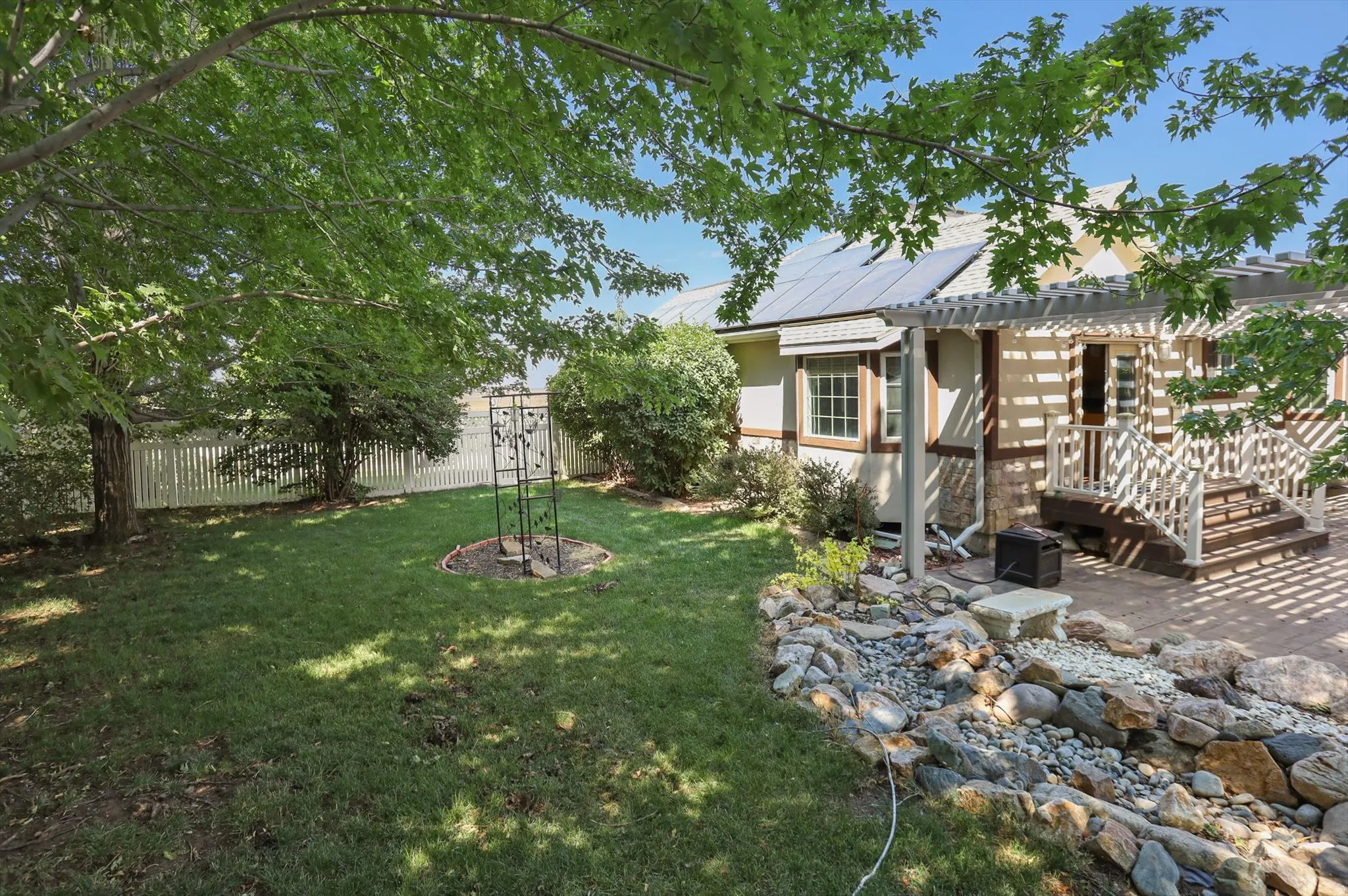 Expansive backyard featuring a manicured lawn, white picket fencing, and a dry riverbed landscaping feature
