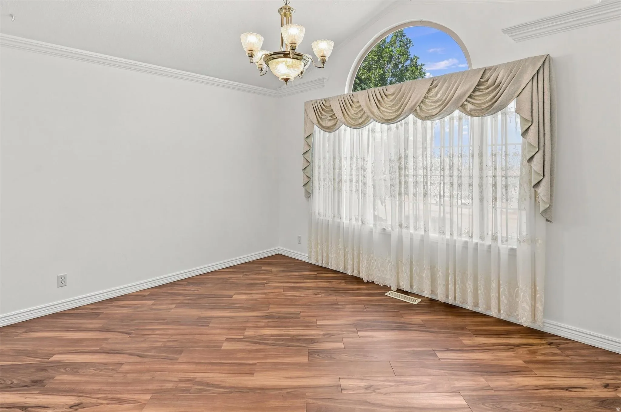 Wood-finish flooring, arched window, and crown molding