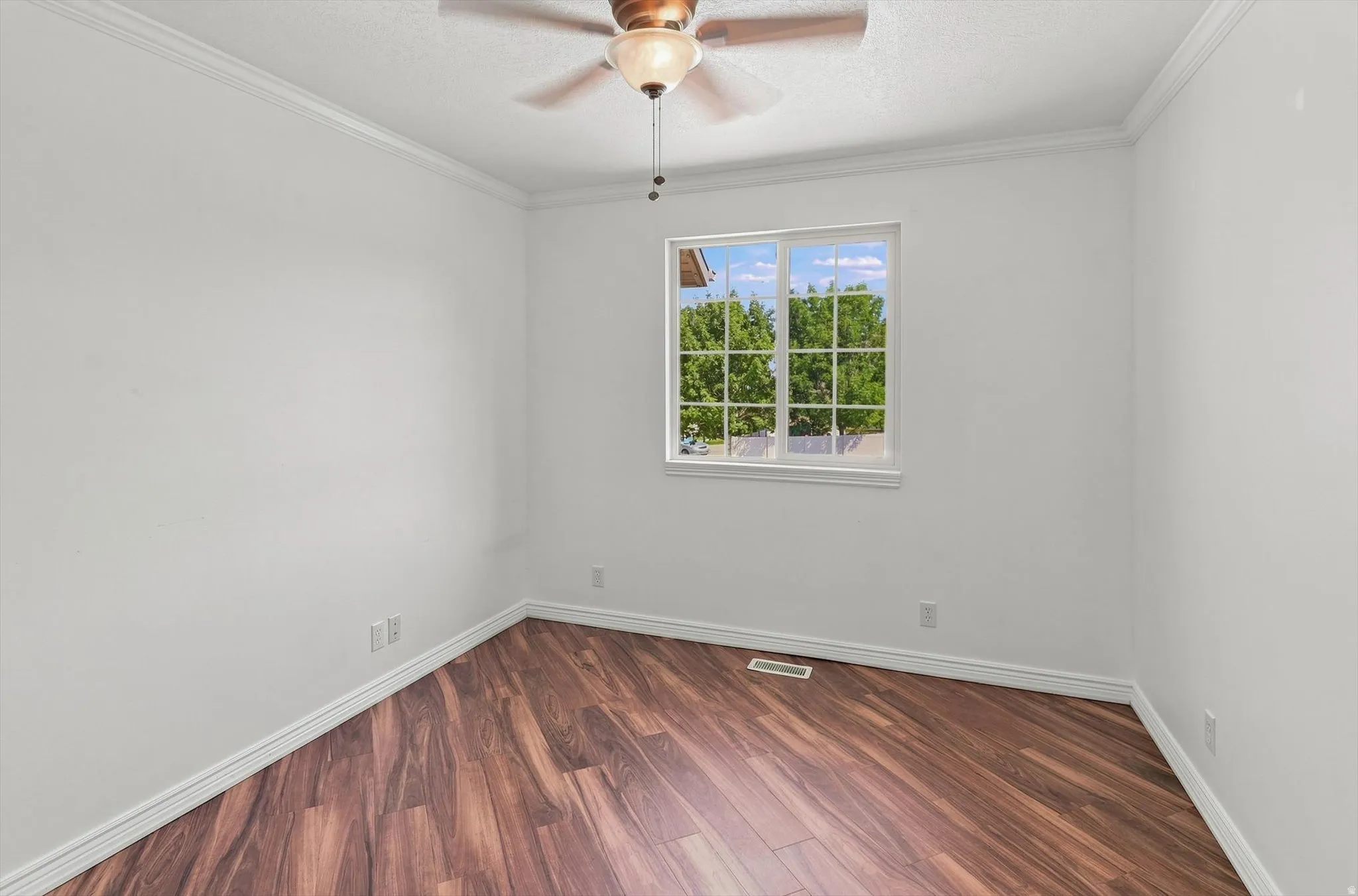 Window with grid pattern, crown molding, wood-finish flooring, ceiling fan with integrated lighting, and white walls