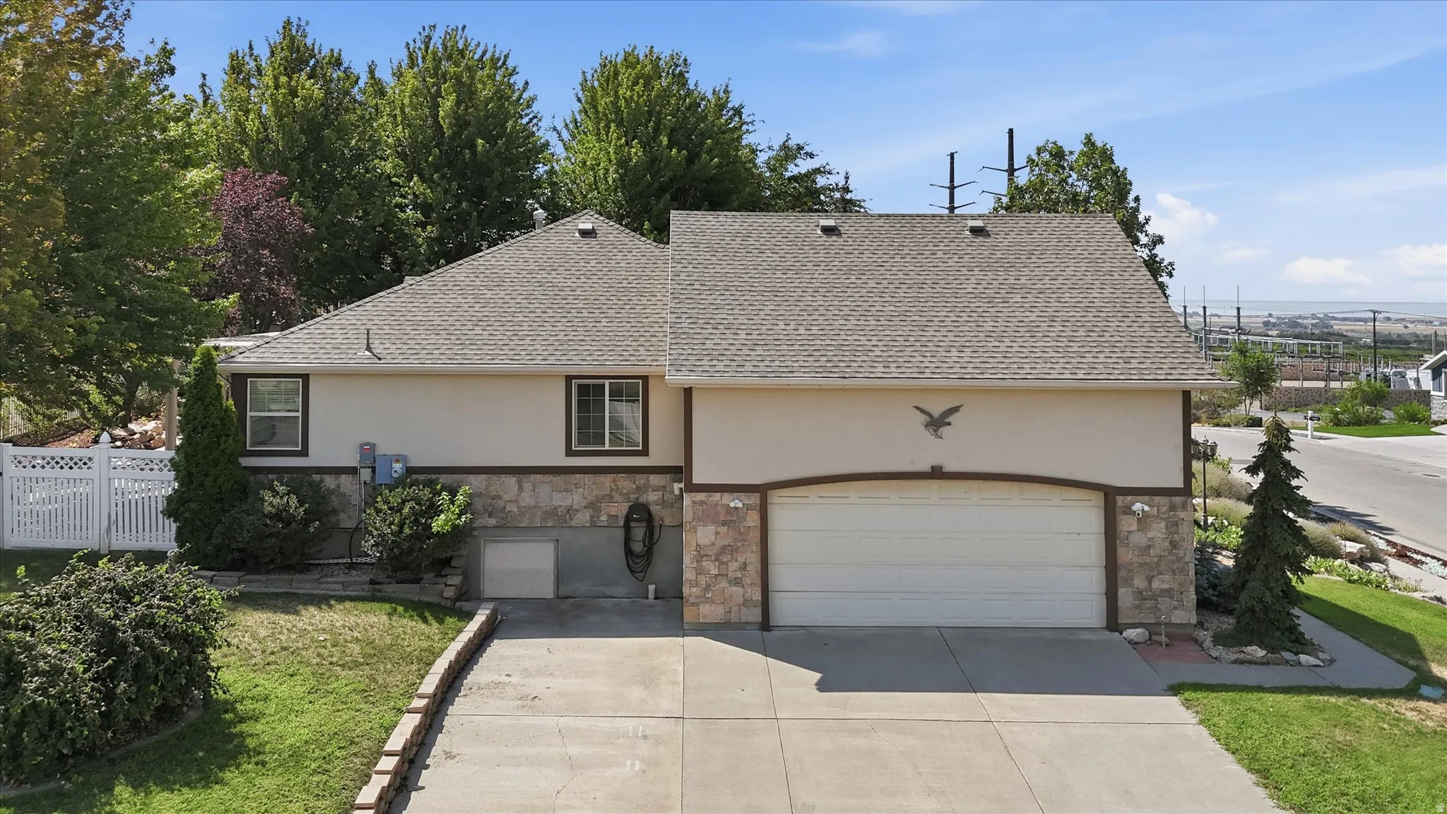 Two-story residence featuring a two-car garage, stone and stucco exterior, and a white picket fence