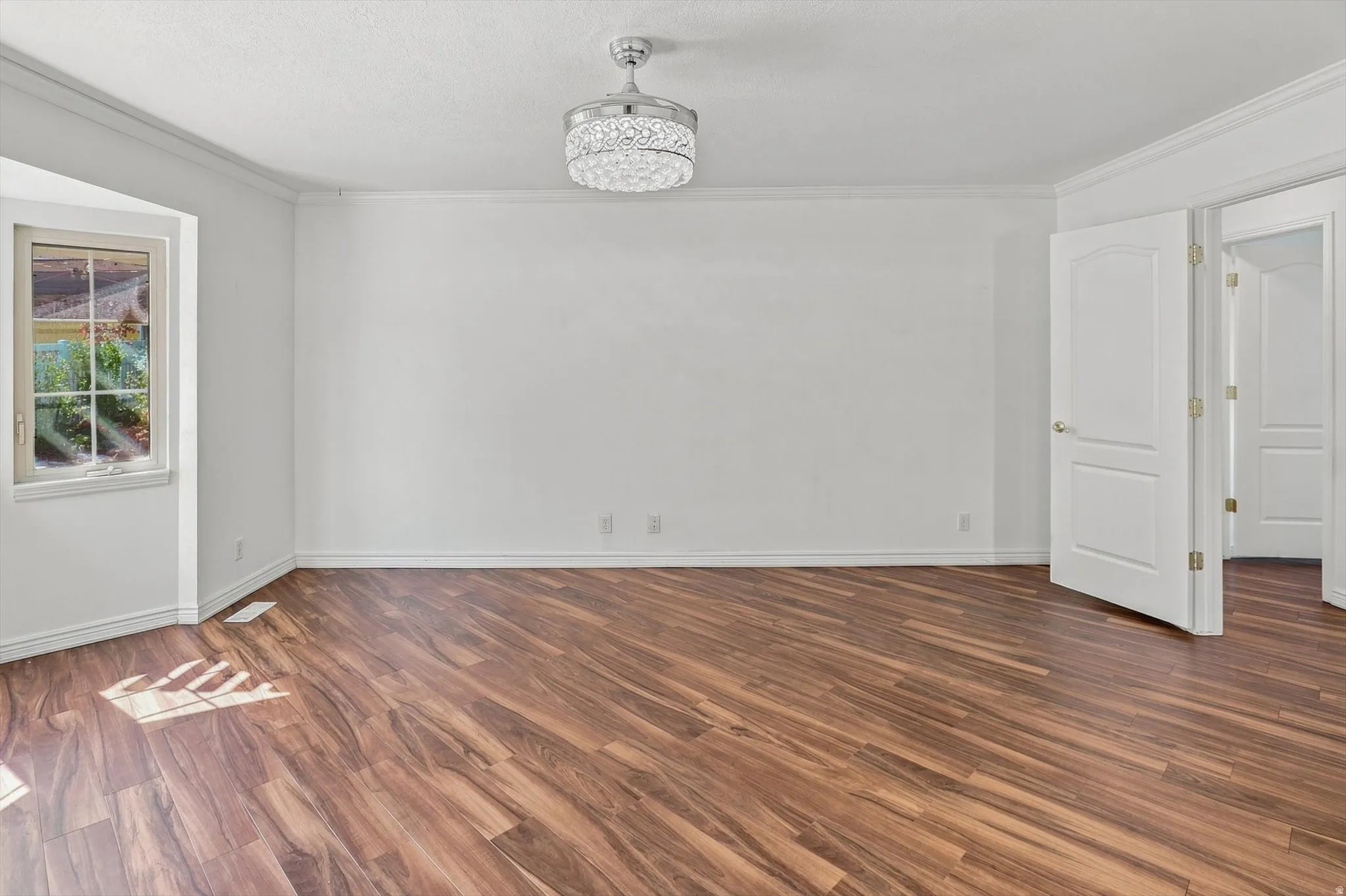 Spacious room featuring wood-finish flooring, white walls, and a decorative ceiling fan
