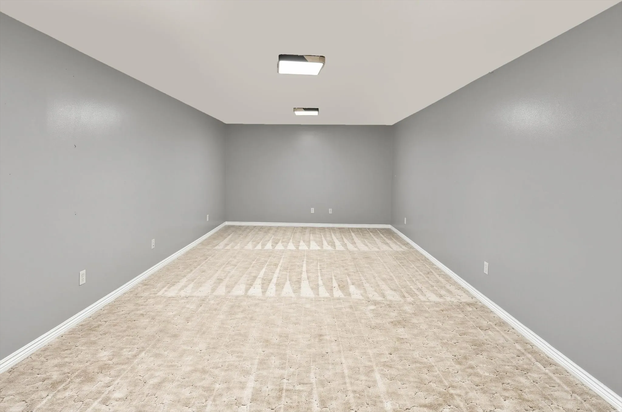 Spacious room with light gray walls, white trim, recessed lighting, and patterned flooring