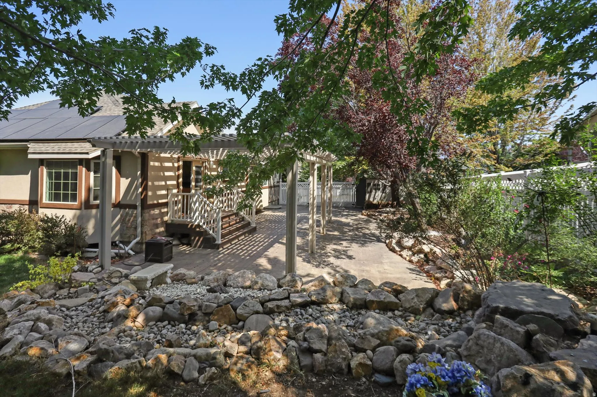 Rear exterior with a stone-accented facade, bay window, and a pergola-covered patio