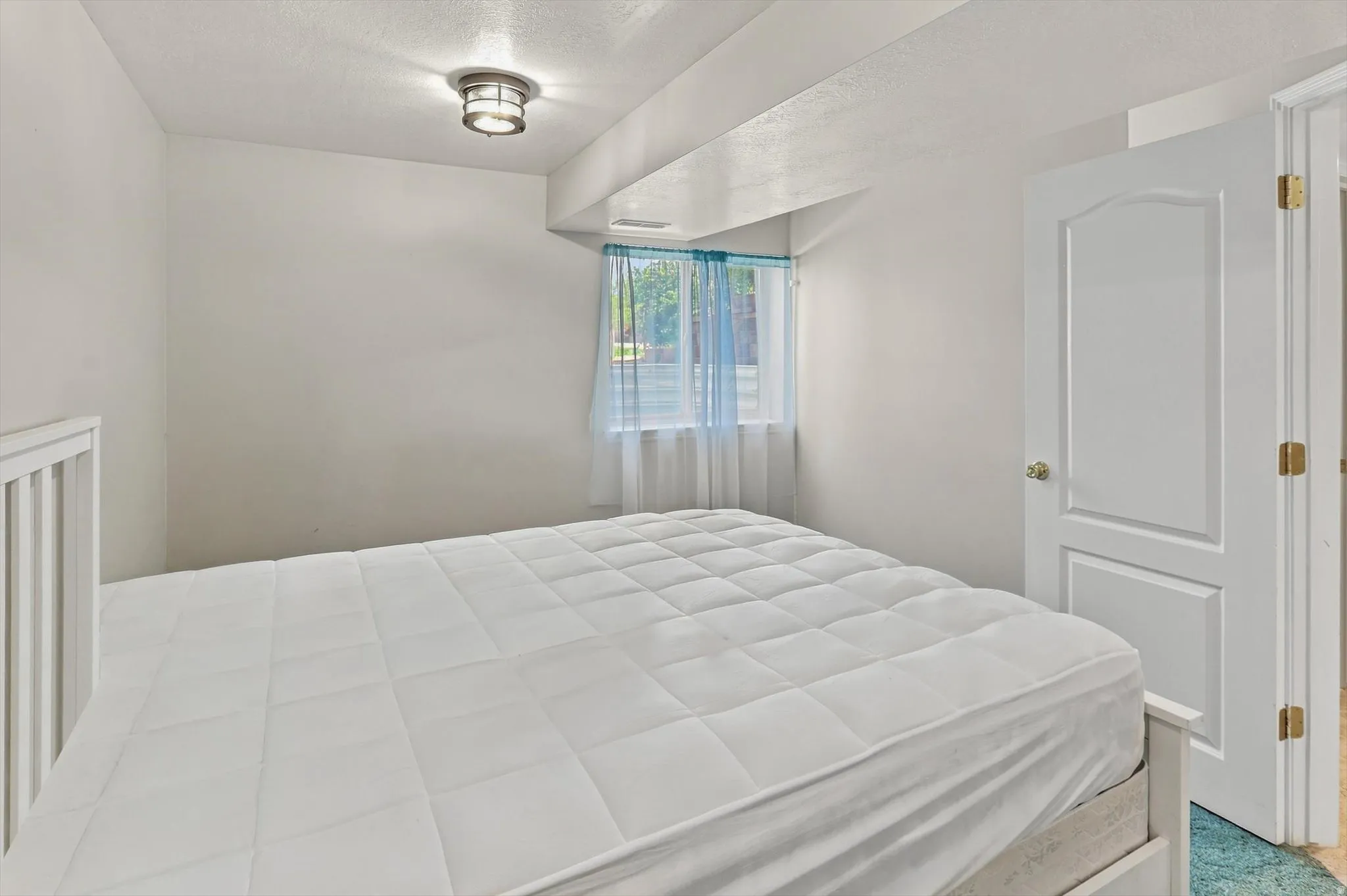 White painted walls with a window, white paneled door, and ceiling-mounted light fixture