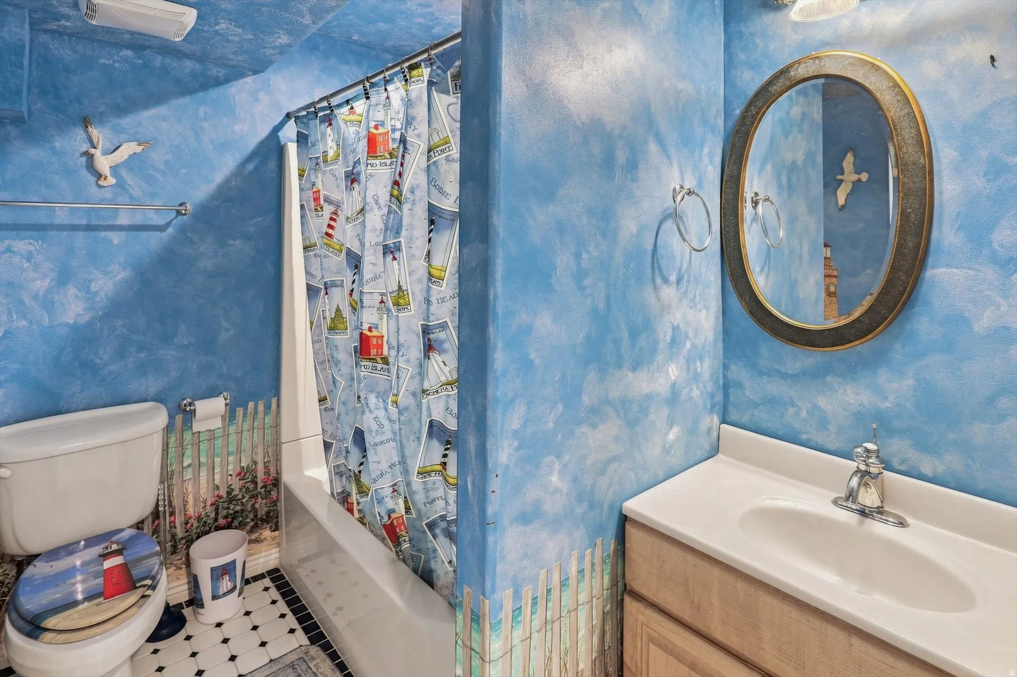 Bathroom featuring a white bathtub, a toilet, an oval-framed mirror, and a single vanity with storage